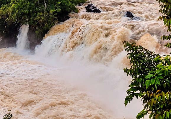 Close view of the main cascade, white water falling past a tree-covered island.